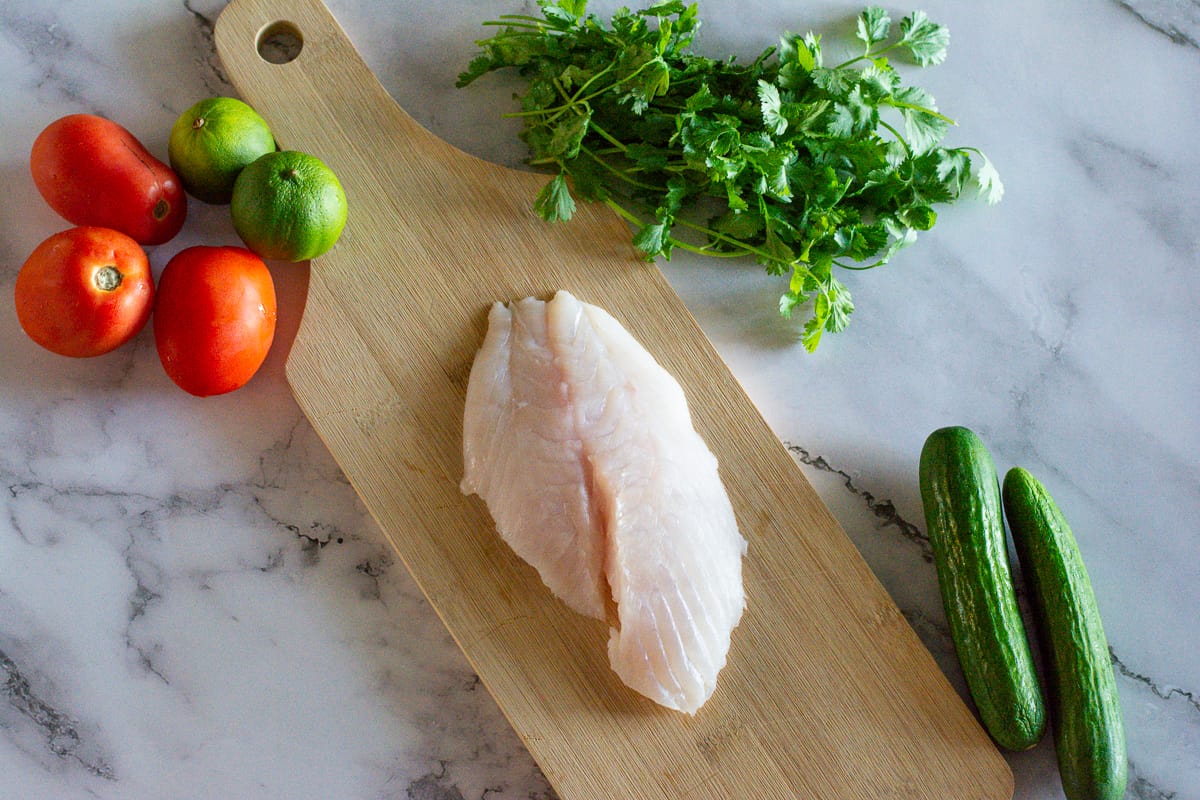 Ceviche ingredients, fish, cucumber, cilantro, tomatoes, limes