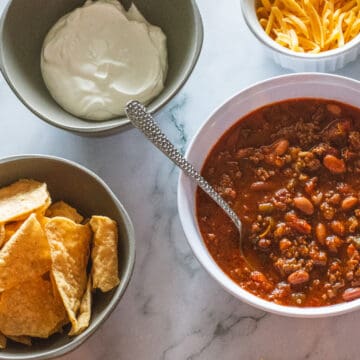 bowl of chili with cheese chips and sour cream