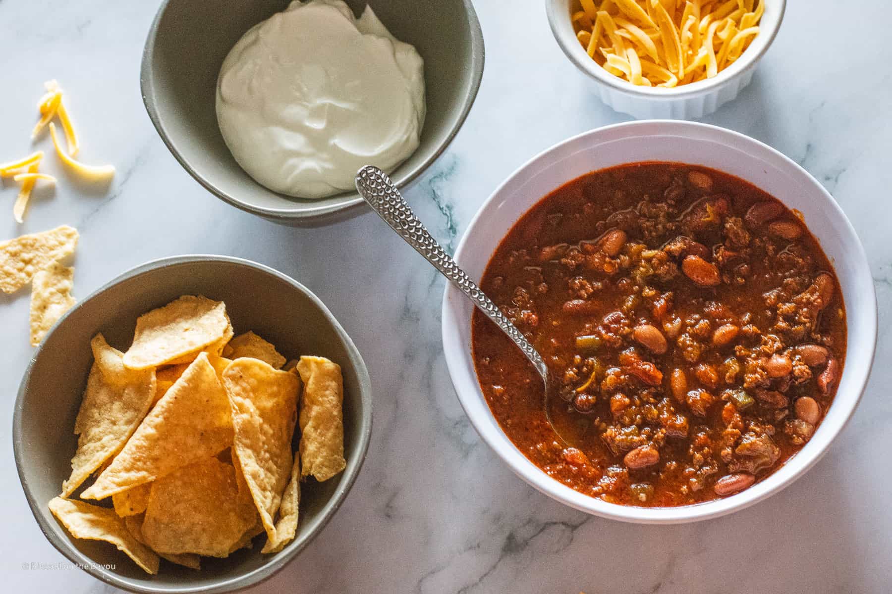 bowl of chili with cheese chips and sour cream