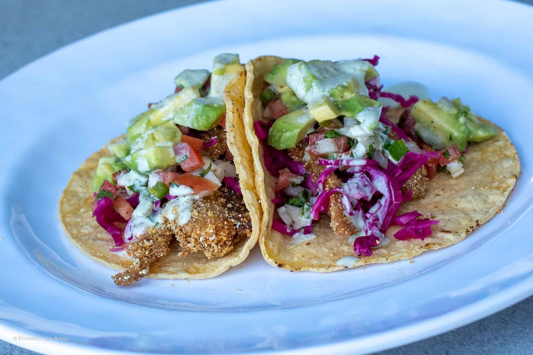Mahi Mahi tacos plated avocado white sauce and pickled cabbage
