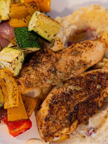 Lemon Garlic Chicken Plated on top of mashed potatoes with roasted veggies and creamy herb sauce
