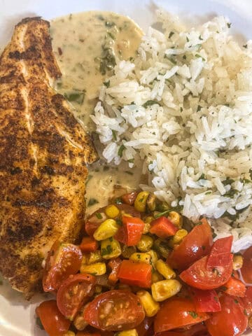 Red Snapper plated with coconut lime sauce and rice with corn salad