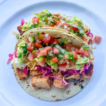 Cajun white fish tacos topped with avocado, pico de gallo, pickled red cabbage, and lime-jalapeño sauce